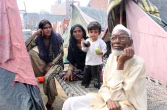 Sham Shamsad, 69 (right), sits with his daughter Naima, 18 (far left) [Sonia Paul/Al Jazeera]
