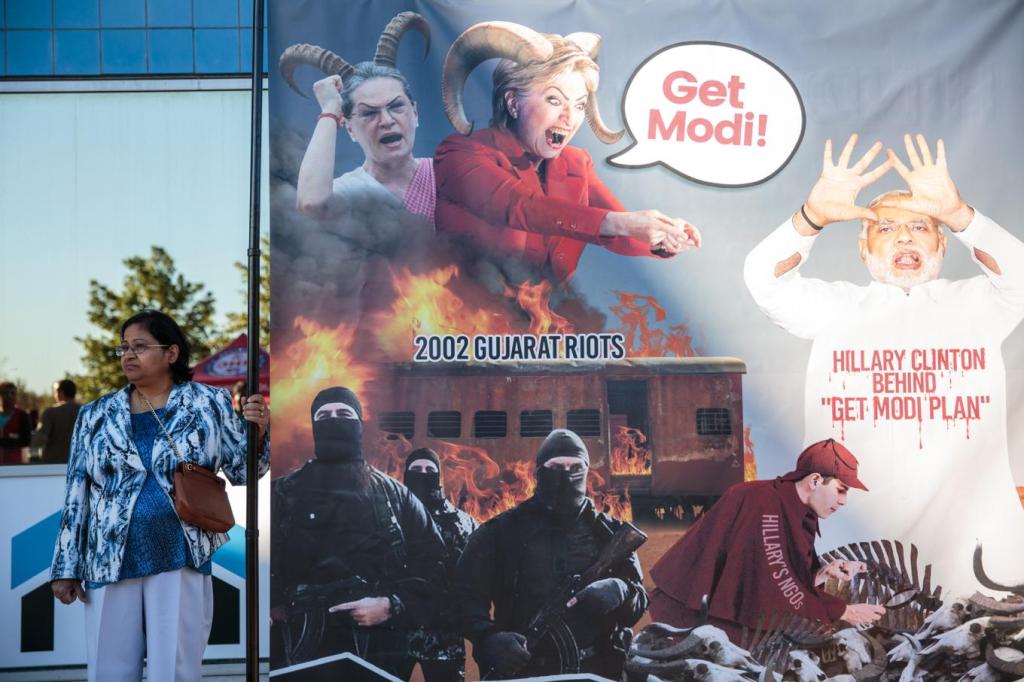 A Donald Trump supporter stands with a sign, arguing that as Secretary of State, Hillary Clinton created a “Get Modi Policy” to falsely accuse India’s Prime Minster of genocide for the 2002 Gujurat riots. Photo by: Sara Hylton